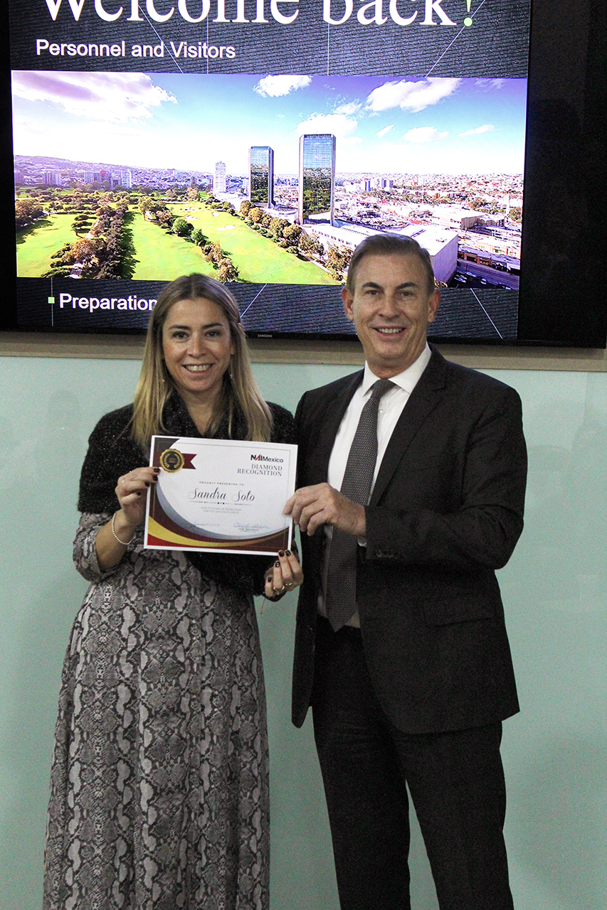 Woman and man holding certificate at professional event with cityscape on screen background